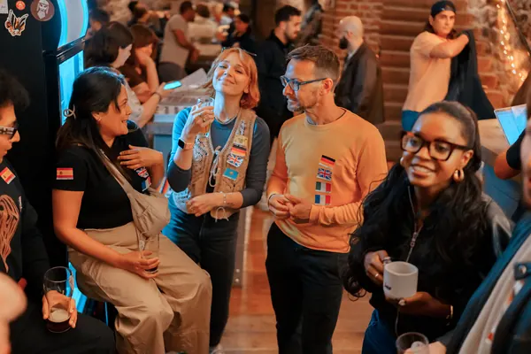 Expats and locals with flag stickers laughing together at the Social Melting Pot social in Bonn