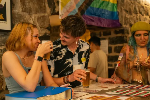 Two guests laughing at the flag sticker table inside °Plato Beer & BBQ at the SMP social in Bonn