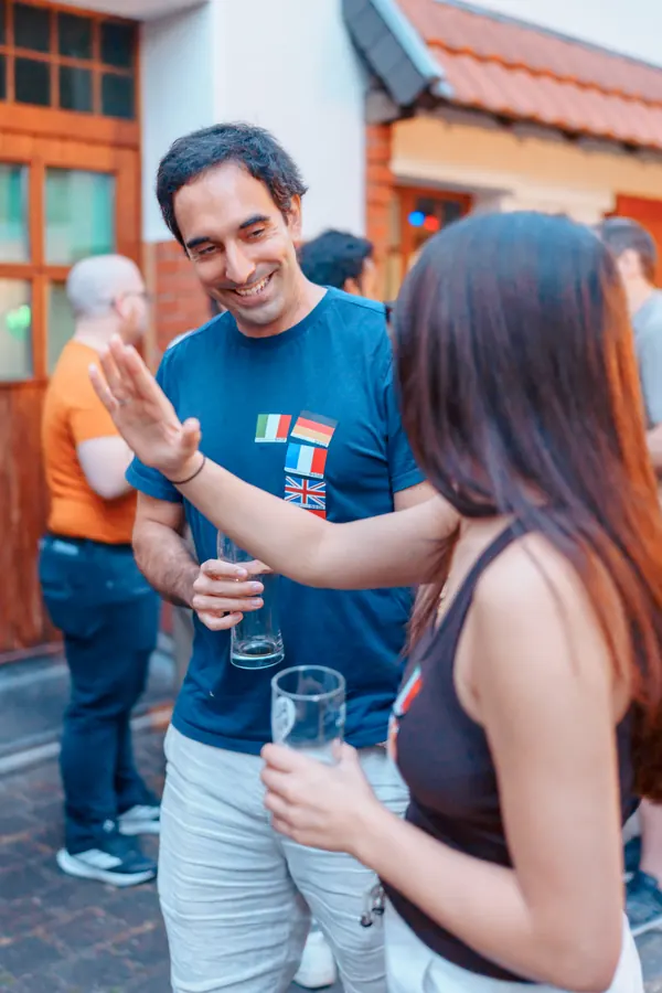 Two guests with flag stickers laughing as they meet in the courtyard at the SMP social in Bonn