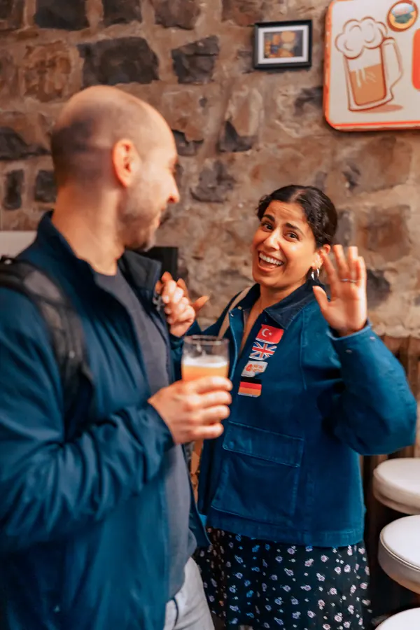 A guest waving and laughing mid-conversation at a Social Melting Pot night at °Plato Beer & BBQ in Bonn