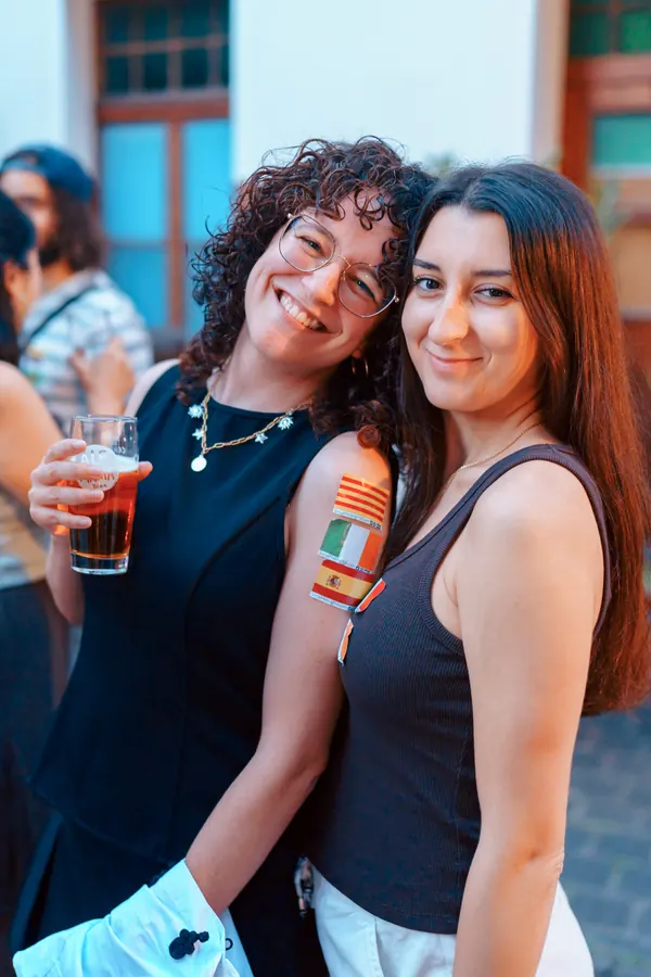 Two guests with language flag stickers hugging and smiling at the Social Melting Pot social in Bonn
