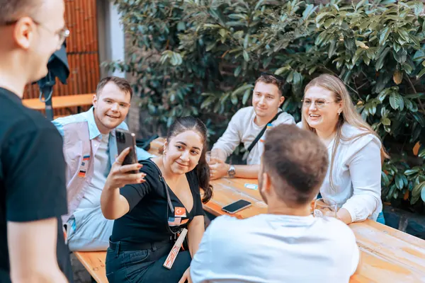 Guests taking a selfie together at a courtyard table at °Plato Beer & BBQ during the social in Bonn
