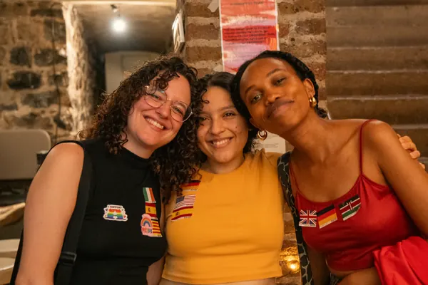Three guests with flag stickers smiling cheek to cheek at the SMP social at °Plato Beer & BBQ in Bonn
