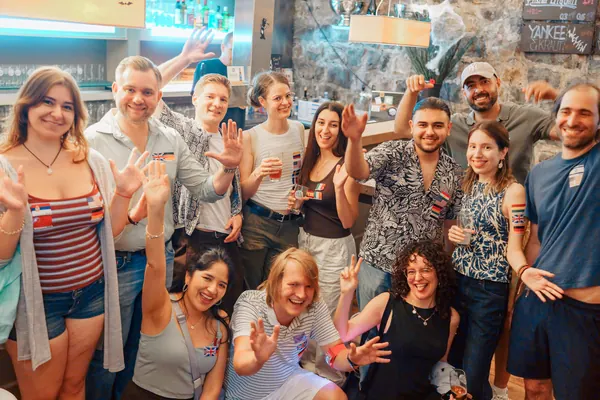 A group of guests waving at the camera at the bar at the Social Melting Pot social in Bonn