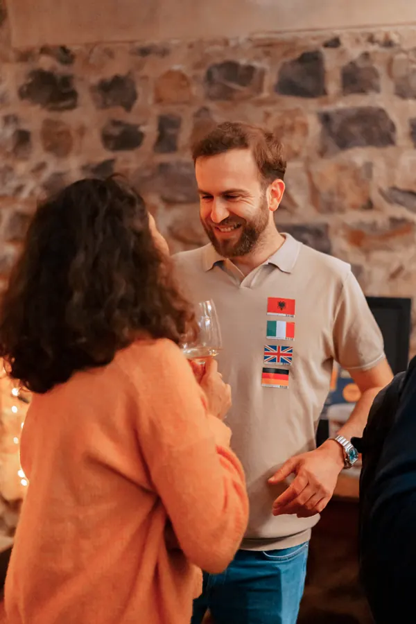Two guests laughing in conversation by the stone wall at a Social Melting Pot night in Bonn