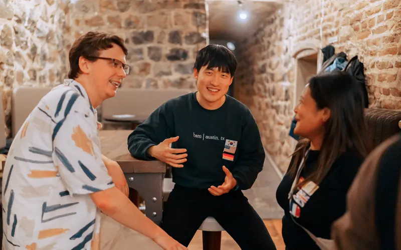 Three guests laughing together at the Social Melting Pot Thursday social at °Plato Beer & BBQ in Bonn