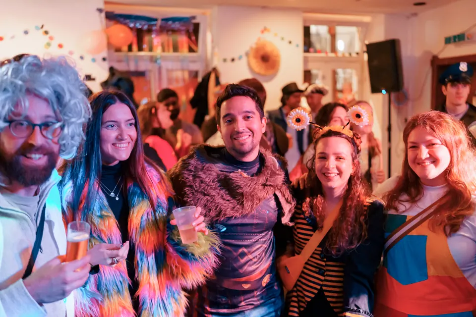 Five friends in carnival costumes smiling together