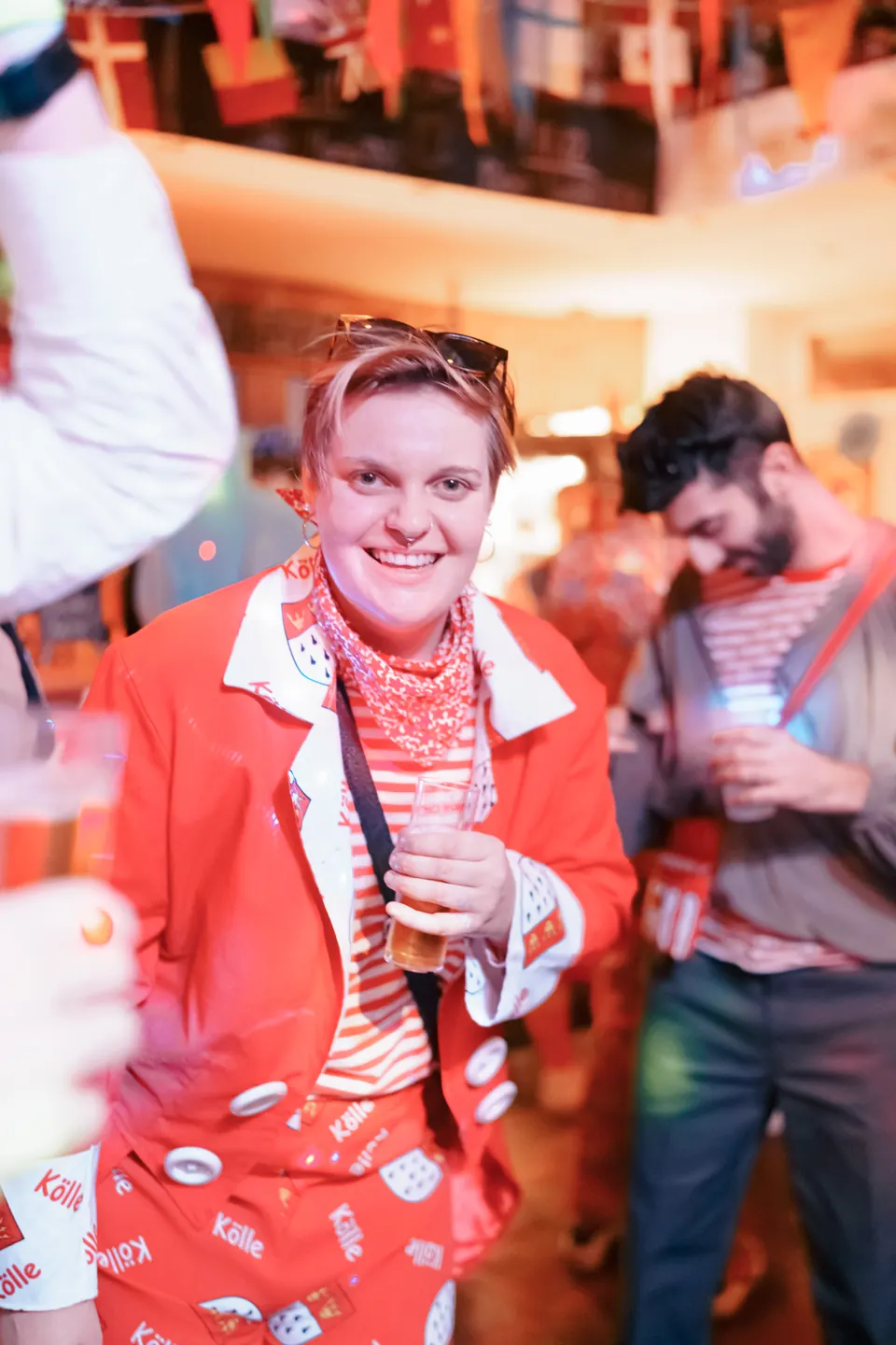 A guest in a red carnival suit with a K&ouml;lle print laughing at Craftbeer Corner
