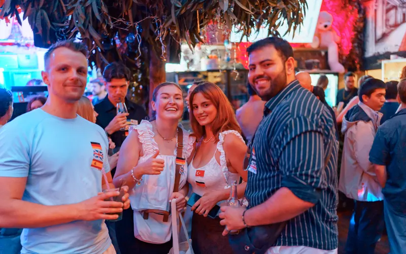 Guests with language flag stickers smiling at the Social Melting Pot Saturday Edition at Goldfinger in Cologne