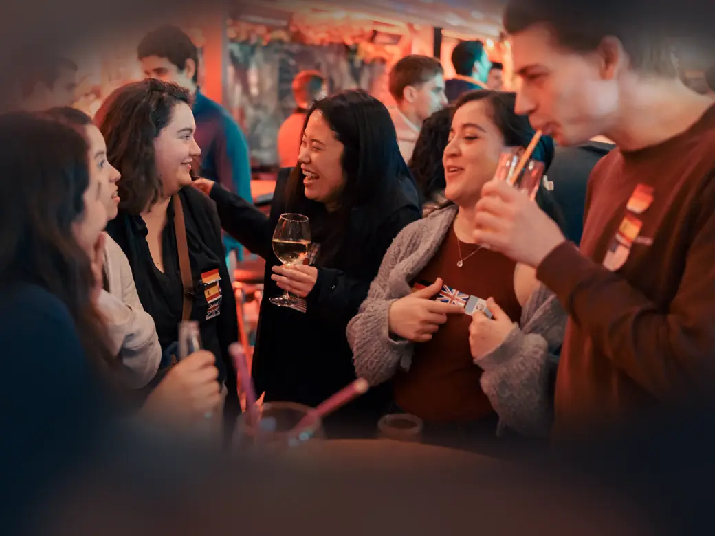 A group of new friends laughing together around a table with drinks at a Social Melting Pot night in Cologne