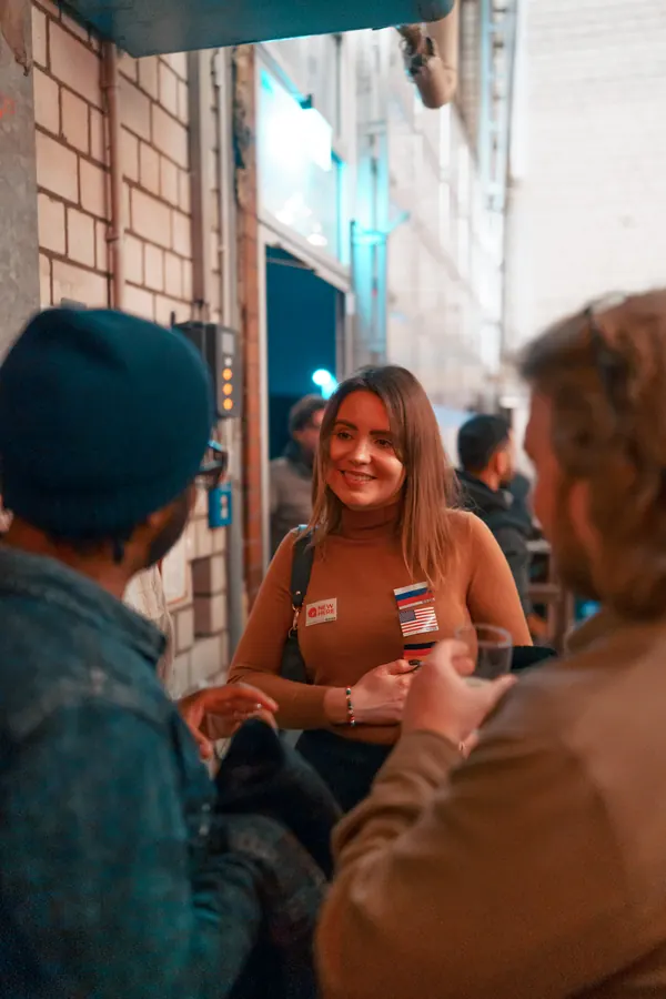 A guest with a flag sticker smiling in conversation at the Thursday social at Brauerei Kürzer in Düsseldorf