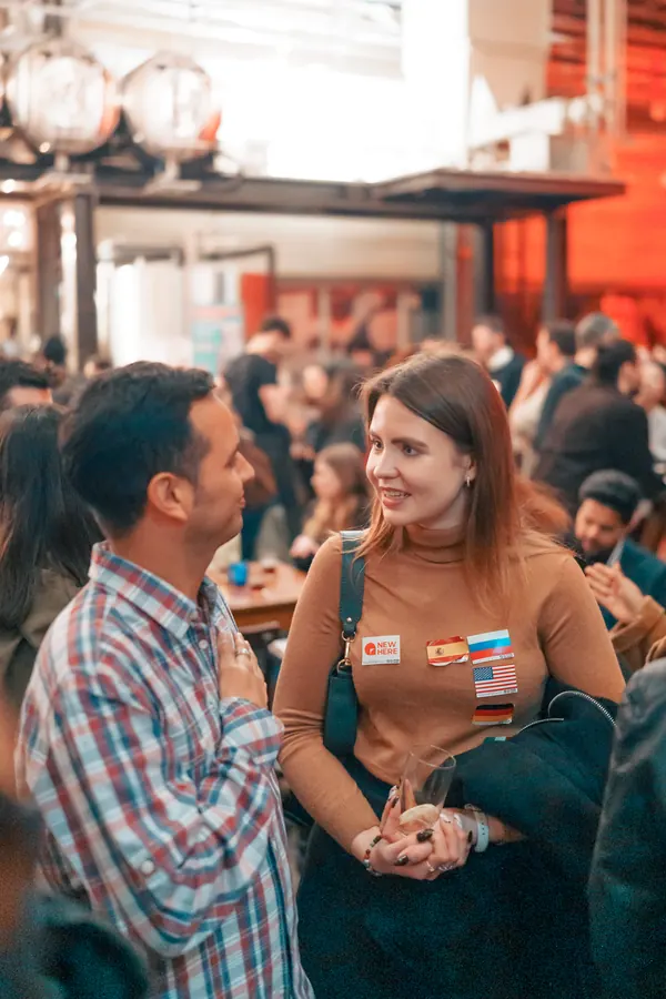 Two guests with flag stickers getting to know each other in the brewery hall at the social in Düsseldorf