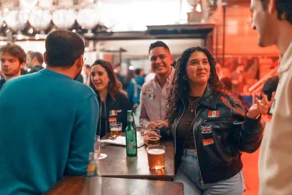 Locals and internationals with flag stickers talking at a table at Brauerei Kürzer in Düsseldorf