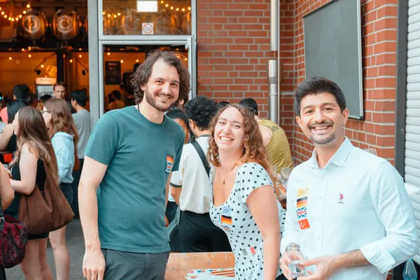 Three guests smiling together outside Brauerei Kürzer during the SMP social in Düsseldorf