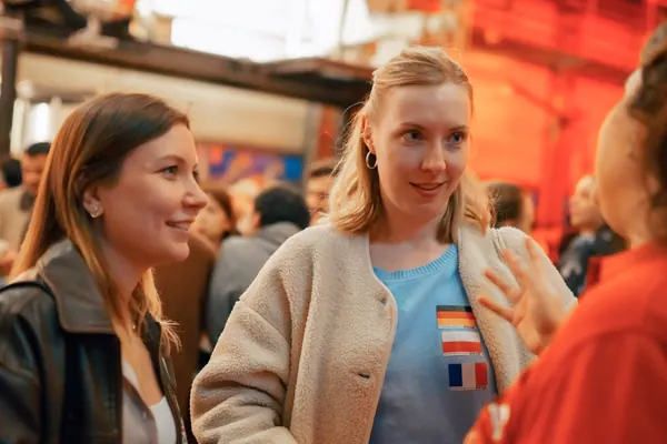 Two guests with flag stickers smiling in conversation at Brauerei Kürzer at the social in Düsseldorf