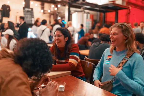 Guests laughing at a long table in the brewery hall at the Social Melting Pot social in Düsseldorf