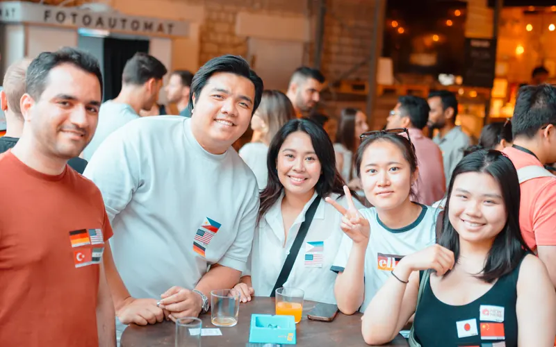 A group of guests with flag stickers smiling at a table at the Thursday social at Brauerei Kürzer in Düsseldorf