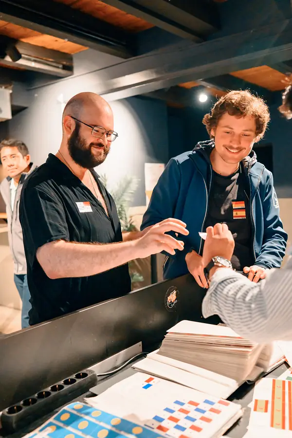 Two SMP team members handing out language flag stickers at the welcome desk at Bar Grüner Jäger in Hamburg