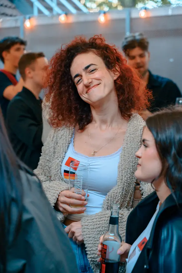 A guest with a language flag sticker smiling in the crowd at a Social Melting Pot night in Hamburg