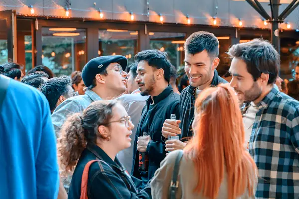A full terrace of internationals and locals talking under string lights at the SMP social in Hamburg