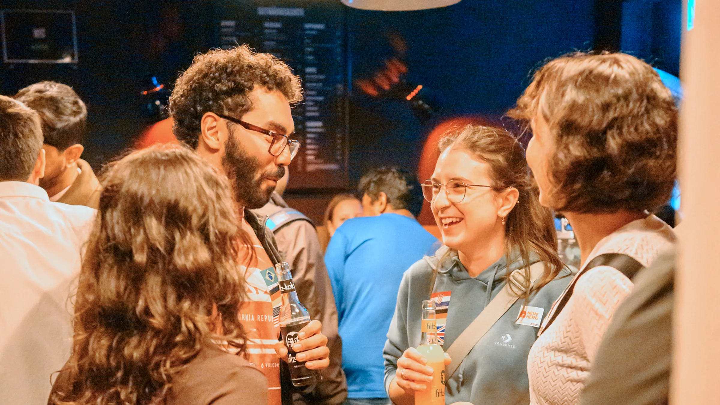 Friends laughing together in a busy Hamburg bar at a Social Melting Pot night