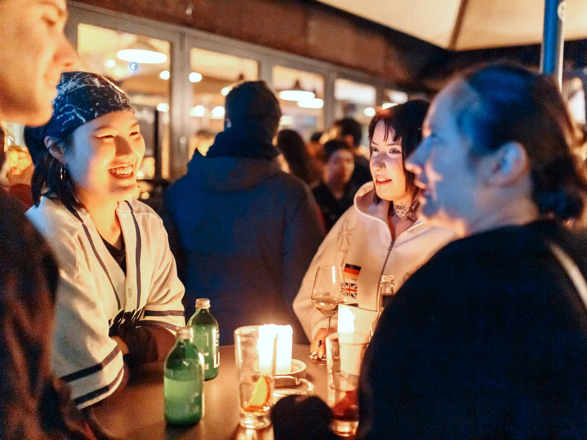 Two women laughing by candlelight at a Social Melting Pot night in Hamburg