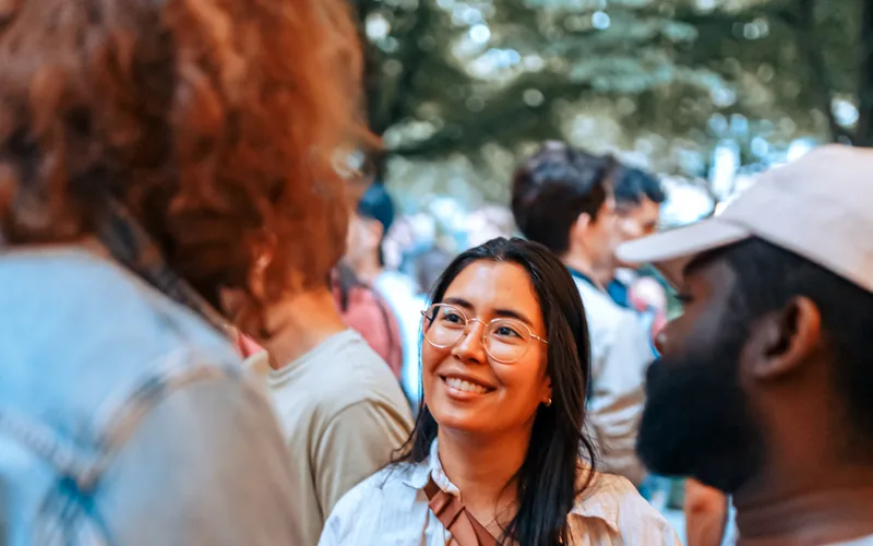 Smiling woman with language flags chatting with friends at a Social Melting Pot night in Hamburg