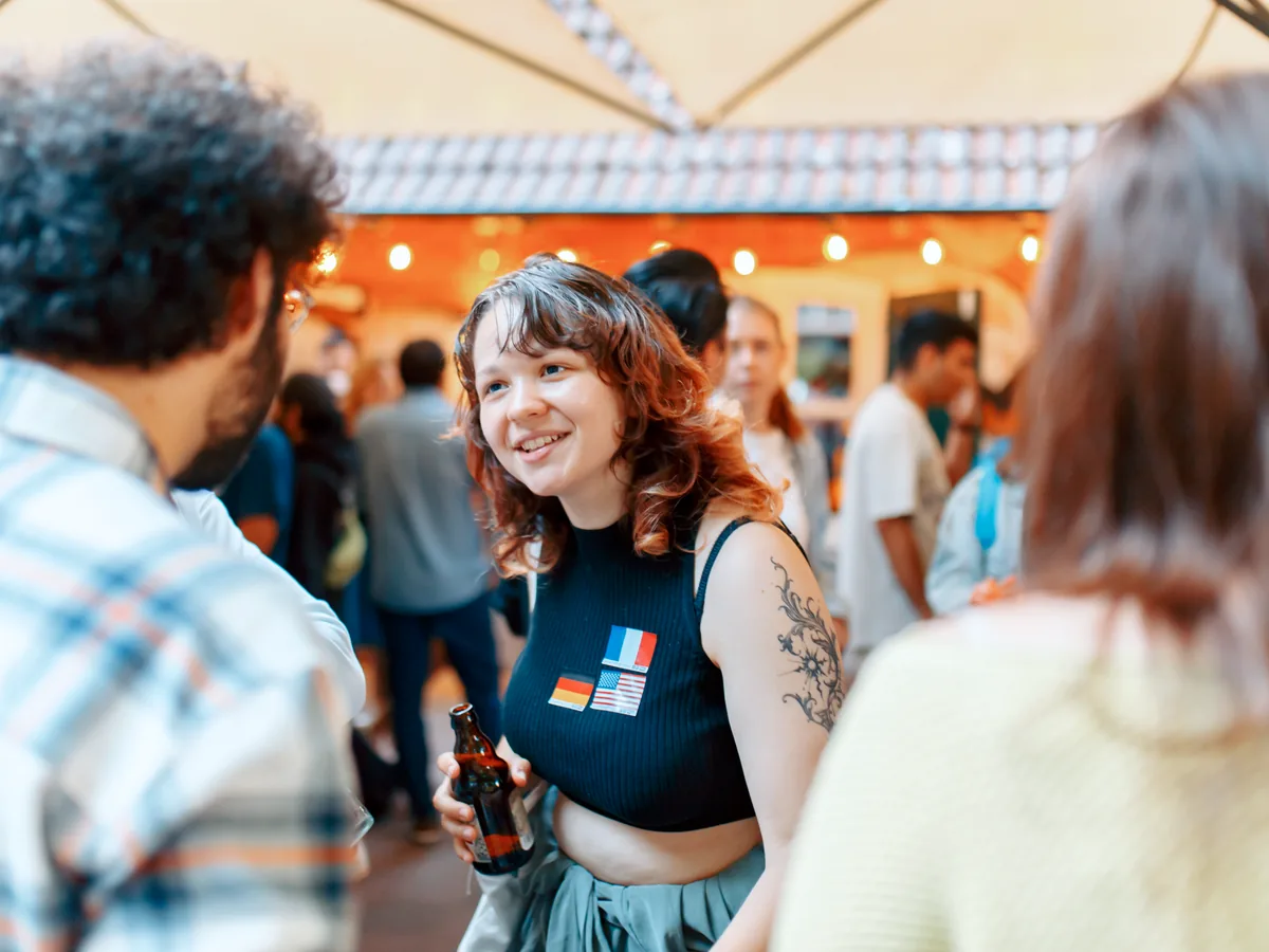 Young woman with flag stickers smiling in conversation on a Hamburg terrace
