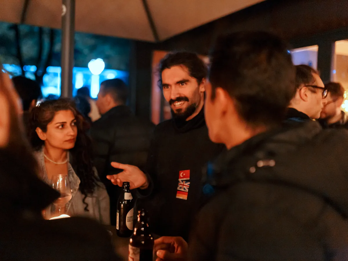 Internationals laughing in conversation under the terrace roof in Hamburg at night