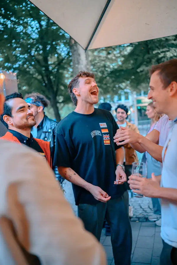 Guests laughing together in a circle on the terrace at Bar Grüner Jäger during the social in Hamburg