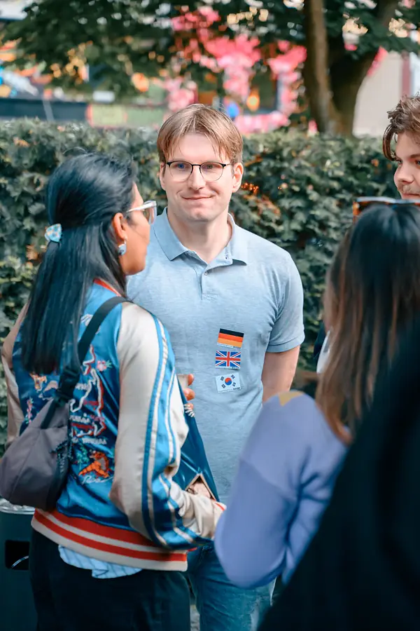 Guests with language flag stickers talking in a small group on the terrace at the SMP social in Hamburg