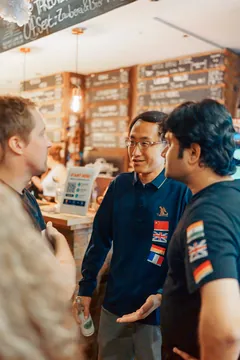 Two guests with language flags on their shirts talking at the bar inside Craftbeer Corner Coeln in Cologne